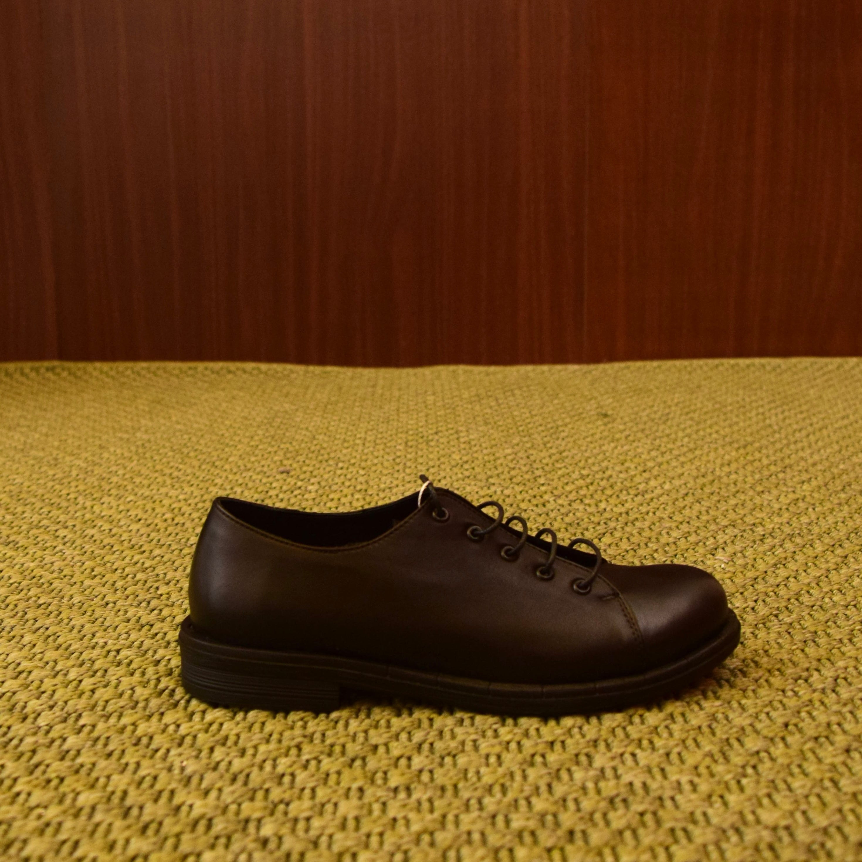 alt="Scarpa Derby stringata in pelle nera con suola coordinata"